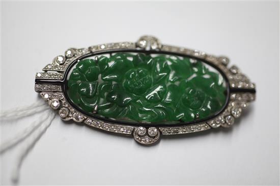 A 1920s/1930s Art Deco white gold?, pierced carved jadeite, diamond and black onyx set oval brooch, 53mm.